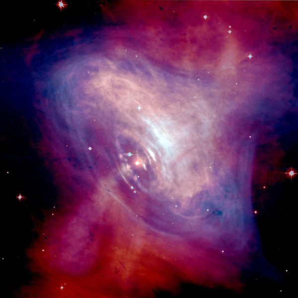 The X-ray emissions (blue/purple) of the pulsar in the crab nebula, shown optically in red. Image credit: Optical: NASA/HST/ASU/J. Hester et al. X-Ray: NASA/CXC/ASU/J. Hester et al.