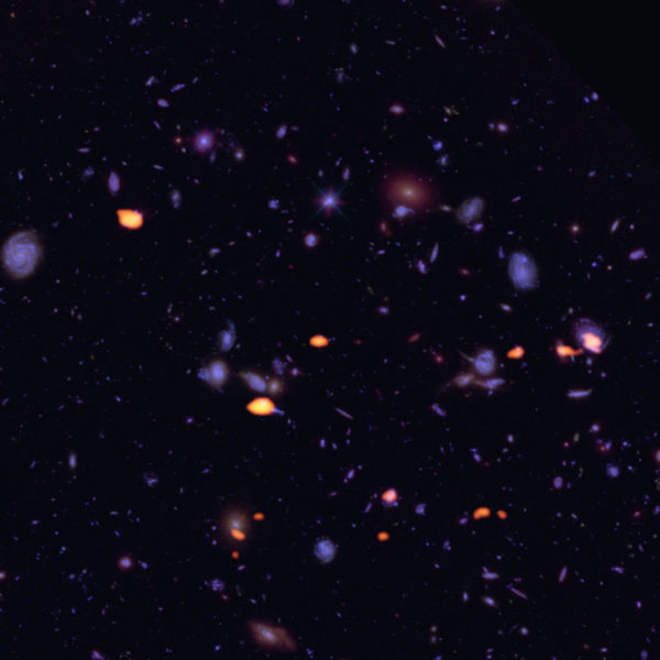 A trove of galaxies, rich in dust and cold gas (indicating star-forming potential) was imaged by ALMA (orange) in the Hubble Ultra Deep Field. Image credit: B. Saxton (NRAO/AUI/NSF); ALMA (ESO/NAOJ/NRAO); NASA/ESA Hubble.