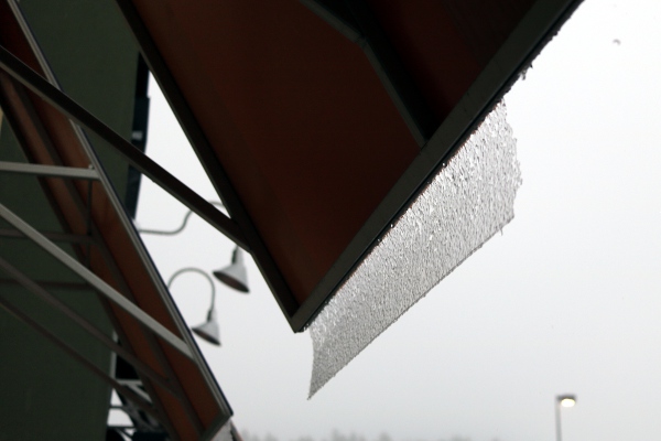 A thin layer of ice in the process of sliding off an awning.