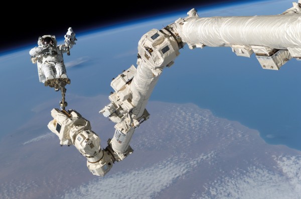 Image credit: NASA, of Astronaut Stephen K. Robinson, STS-114 mission specialist, anchored to a foot restraint on the International Space Station’s Canadarm2.