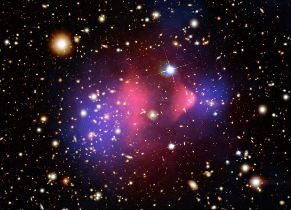 The Bullet Cluster, the first colliding galaxy clusters showing the separation between normal matter (pink, from the X-rays) and dark matter (blue, from gravitational lensing). Image credit: X-ray: NASA/CXC/CfA/M. Markevitch et al.; Lensing Map: NASA/STScI; ESO WFI; Magellan/U. Arizona/D. Clowe et al. Optical: NASA/STScI; Magellan/U. Arizona/D. Clowe et al.