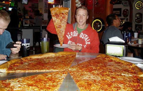 A guy eating a big slice of big pizza at Big Lou's. Image credit: Sam DeLong of flickr.