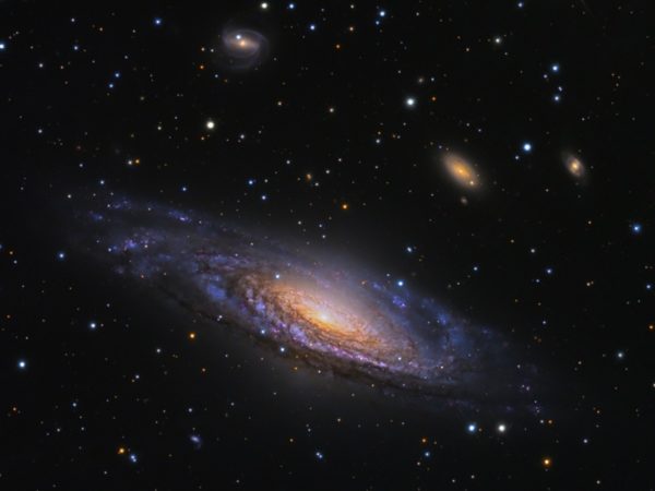 The galaxy NGC 7331 and smaller, more distant galaxies beyond it. The farther away we look, the farther back in time we see. We will eventually reach a point where no galaxies at all have formed if we go back far enough. Image credit: Adam Block/Mount Lemmon SkyCenter/University of Arizona.