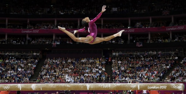 Gabby Douglas, Olympic gymnast, in mid-leap, sailing above a balance beam